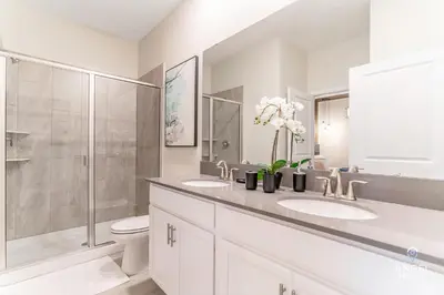 a white bathroom with two sinks and a shower at In-Home Arcade, Themed Bedrooms, Resort Lazy River in Kissimmee