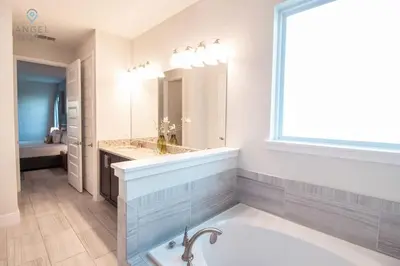 a bathroom with a tub and a sink and a window at Palatial 9BR Private Pool Villa Theater Game Room in Orlando