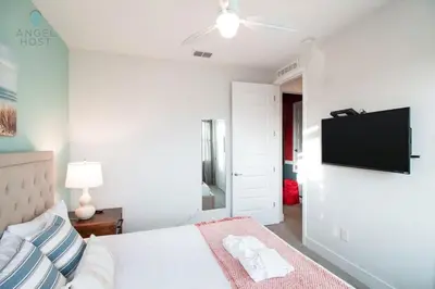 a white bedroom with a bed and a flat screen tv at Palatial 9BR Private Pool Villa Theater Game Room in Orlando