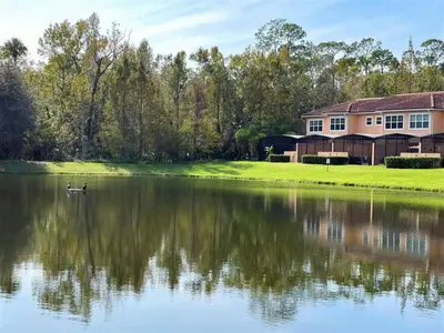 a house next to a lake with a duck in the water at Resort Home near Disney Themed Jacuzzi Pool 2609 in Orlando
