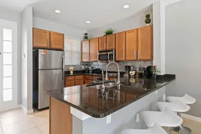 a kitchen with a granite counter top and wooden cabinets at Resort Home by Disney Themed Jacuzzi Pool 2666 in Orlando