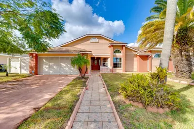 a house with palm trees and a driveway at Furnished Lanai and Lake View Quiet Home in Orlando in Kissimmee
