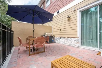 a patio with a table with an umbrella and chairs at The Mouse PlayHouse in Orlando