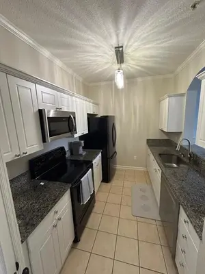 a kitchen with white cabinets and black appliances at Beautiful Apartment Near Disney in Kissimmee