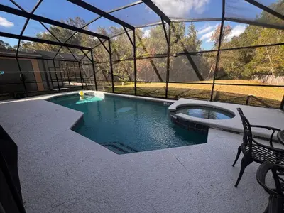 a swimming pool with a chair and a bench next to it at Charming Family Friendly Home in Kissimmee