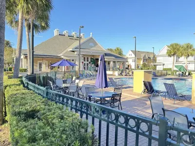 a fence with tables and chairs and a pool at 4 Bedroom 3 Bathroom Villas At SevenDwarfs 31-107 in Kissimmee