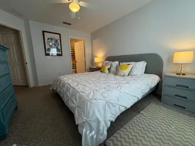 a bedroom with a bed and a blue dresser and lamp at 4 Bedroom 3 Bathroom Villas At SevenDwarfs 28-107 in Kissimmee
