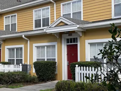 a yellow house with a red door and a white fence at 3 Bedroom 2 Bathroom Villas At SevenDwarfs 15-103 in Kissimmee