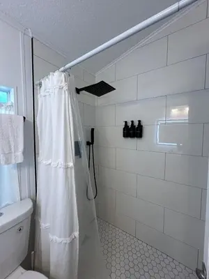 a bathroom with a shower curtain and a toilet at Your home away from home! Entire cottage- Disney in Kissimmee