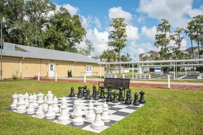 a chess board and a bench in a yard at Your home away from home! Entire cottage- Disney in Kissimmee