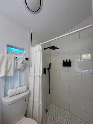 a white bathroom with a shower and a toilet at Your home away from home! Entire cottage- Disney in Kissimmee