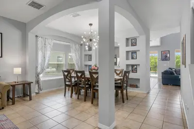 a dining room and living room with a table and chairs at La Isla Retreat - amazing 6 bedroom pool house near Disney Parks in Kissimmee