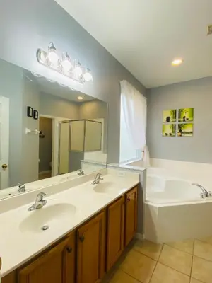 a bathroom with two sinks and a large mirror at La Isla Retreat - amazing 6 bedroom pool house near Disney Parks in Kissimmee