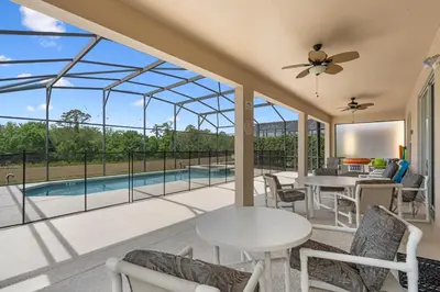 a patio with a table and chairs and a pool at La Isla Retreat - amazing 6 bedroom pool house near Disney Parks in Kissimmee