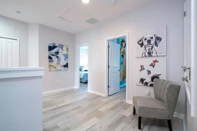 a living room with a chair and paintings on the wall at Luxury Lakeview Home Private Pool 2687 in Kissimmee