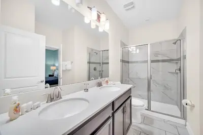 a white bathroom with two sinks and a shower at Lakefront Luxury Retreat Private Pool & Movie Theater 367 in Kissimmee