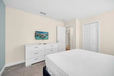 a white bedroom with a bed and a dresser at Lakefront Luxury Retreat Private Pool & Movie Theater 367 in Kissimmee