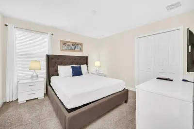a white bedroom with a bed and a dresser at Lakefront Luxury Retreat Private Pool & Movie Theater 367 in Kissimmee