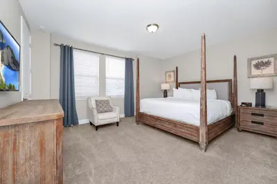 a bedroom with a large bed and a chair at Spacious Home With Private Pool, Themed And Game Room Near Disney With Waterpark & Resort Access - 341Pn in Kissimmee