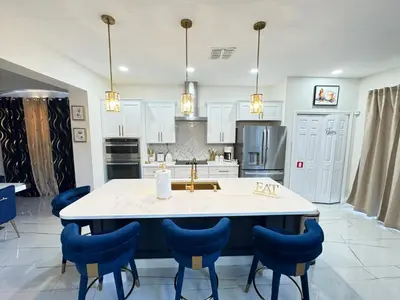 a kitchen with a large island with blue chairs at Bloomslake Resort in Kissimmee