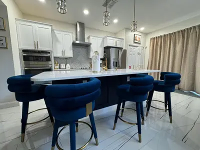 a kitchen with white cabinets and blue bar stools at Bloomslake Resort in Kissimmee