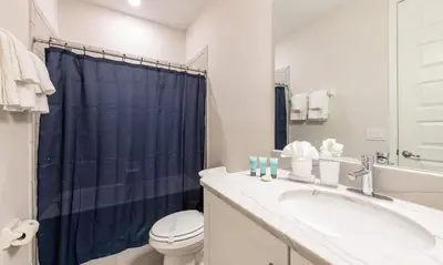 a bathroom with a toilet and a blue shower curtain at 5 Star Villa on Orlando’s most Exclusive Encore Resort at Reunion Orlando Villa 4507 in Orlando