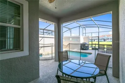 a glass table and chairs on a balcony with a pool at Luxury Townhome on Storey Lake Resort Orlando Townhome 5523 in Kissimmee