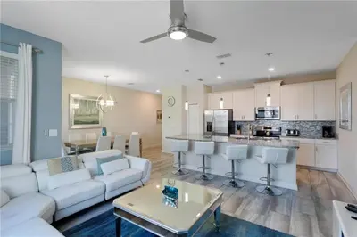 a living room with a white couch and a kitchen at Luxury Townhome on Storey Lake Resort Orlando Townhome 5523 in Kissimmee