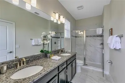 a white bathroom with two sinks and a shower at You Will Love this 5 Star Villa located on Storey Lake Resort Orlando villa 5492 in Kissimmee