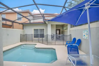a pool with two blue chairs and an umbrella at Luxury 5 Star Villa on Paradise Palms ResortMinutes from Disney World Orlando Townhome 5502 in Kissimmee