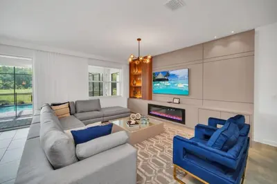 a living room with a couch and two blue chairs at Modern 9 Bedroom Oasis for Large Groups 6272 in Kissimmee