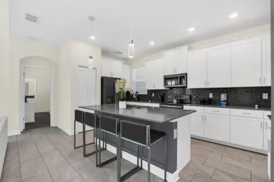 a kitchen with white cabinets and a black counter top at Escape to a 5 Bedroom Villa in Paradise 6316 in Kissimmee