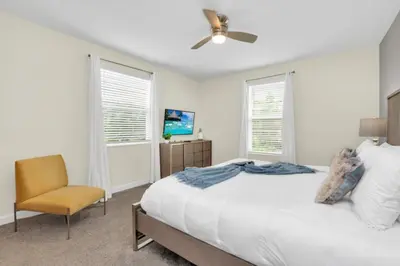 a white bedroom with a bed and a chair at Escape to a 5 Bedroom Villa in Paradise 6316 in Kissimmee