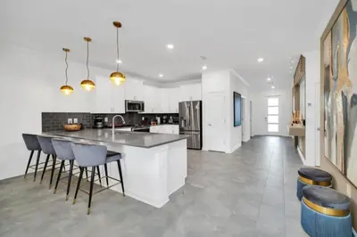 a kitchen with white cabinets and a counter and stools at Family-Friendly Villa with 9 Bedrooms 6317 in Kissimmee