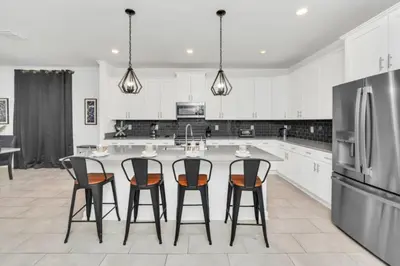 a kitchen with white cabinets and a large island with bar stools at Elegant Villa Retreat with Private Pool 6328 in Kissimmee