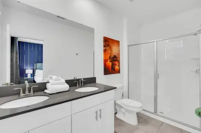 a white bathroom with two sinks and a toilet at Elegant Villa Retreat with Private Pool 6328 in Kissimmee