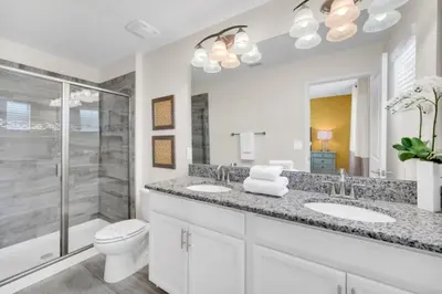 a bathroom with a toilet and two sinks and a shower at 6 Bedroom Villa with Tennis Court Gym 6332 in Kissimmee