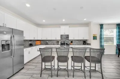 a kitchen with a table with chairs and a refrigerator at 6 Bedroom Villa with Tennis Court Gym 6332 in Kissimmee