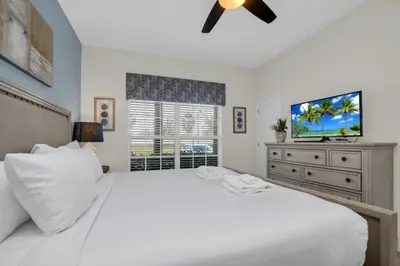 a bedroom with a white bed and a flat screen tv at Modern 4 Bedroom Villa near Beach Shopping 6335 in Kissimmee