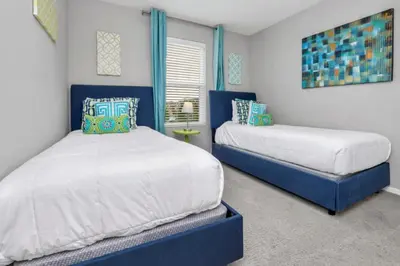 two beds in a bedroom with blue and white at Cozy 4BR Cottage with Fireplace 6379 in Kissimmee