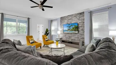 a living room with a couch and a tv at Rent the Perfect 8 Bedroom Villa on Storey Lake Resort Orlando Villa 6293 in Kissimmee