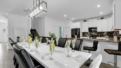 a dining room with a white table and black chairs at Rent the Perfect 8 Bedroom Villa on Storey Lake Resort Orlando Villa 6293 in Kissimmee