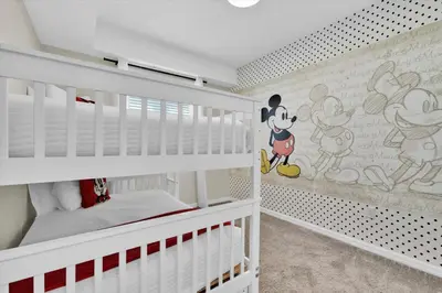 a bedroom with white bunk beds with mickey mouse wallpaper at Book Now: Orlando Condo 6439 at Storey Lake Resort in Kissimmee