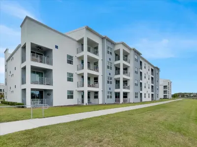 a large white apartment building with a grass field at Book Now: Orlando Condo 6439 at Storey Lake Resort in Kissimmee