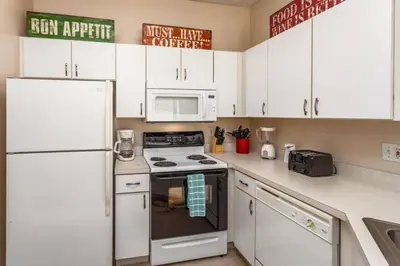 a kitchen with white cabinets and a stove and microwave at Stay Near Disney at Orlando Townhome 6444 Sleeps 8 in Kissimmee