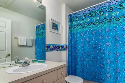 a bathroom with a blue shower curtain and a sink at 5-Star Orlando Townhome 6446: Family Fun Awaits in Kissimmee