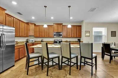 a kitchen with wooden cabinets and a table with chairs at 5-Star Orlando Villa 6452: Family Fun Resort Access in Kissimmee