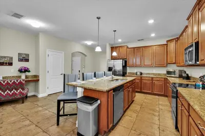 a large kitchen with wooden cabinets and a large island at 5-Star Orlando Villa 6452: Family Fun Resort Access in Kissimmee