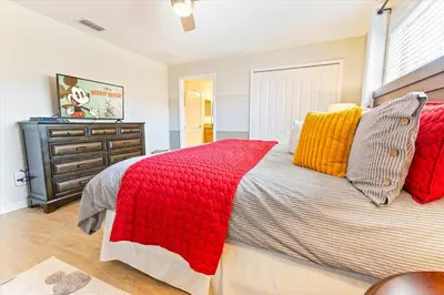 a bedroom with a large bed with red and yellow pillows at Orlando Townhome 6453: Your Private Pool Getaway in Kissimmee