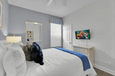 a bedroom with a white bed and a television at Orlando Villa 6469: 6BR Home Near Disney Parks in Kissimmee